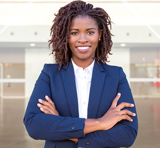 A young woman wearing a suit jacket and smiling, showing off her straighter, healthier smile