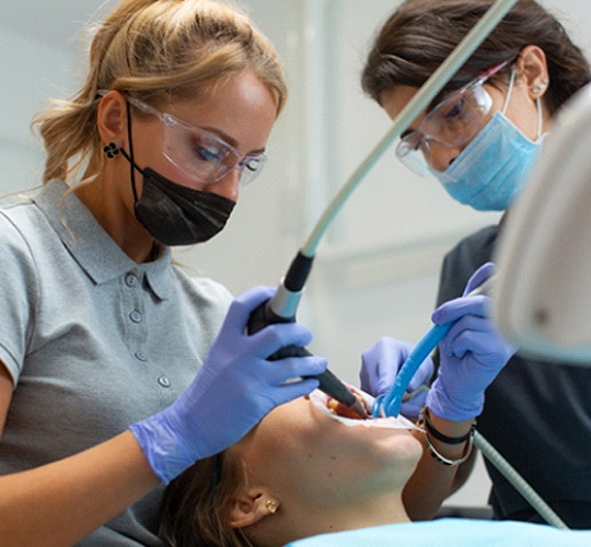 A dentist and dental assistant performing an orthodontic procedure on a female patient