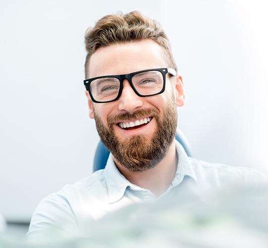 patient smiling while sitting in dental chair 