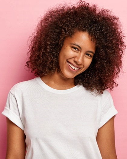 A young woman wearing a white t-shirt and smiling in preparation to eliminate her gapped teeth in Westport with Invisalign