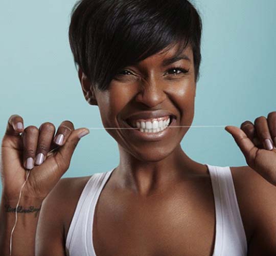 Woman practicing dental implant care in Westport by flossing