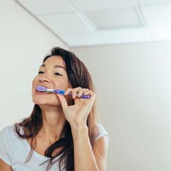 Woman brushing her teeth to protect her dental implants in Westport