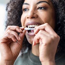 a woman putting aligners over her teeth