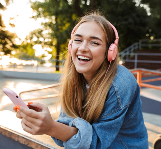 Teen girl smiling while listening to music outside