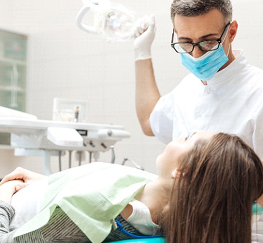 A female patient having her mouth checked by a dentist