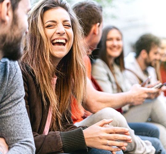 A young woman smiling and laughing with her friends and showing off her new veneers