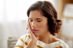 a young woman holding her cheek in pain due to a toothache