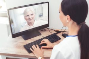 a female dentist providing teledentistry services for an elderly patient