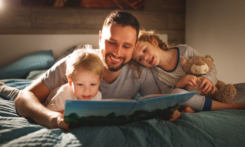 a father reading a book to his two children at night before bed