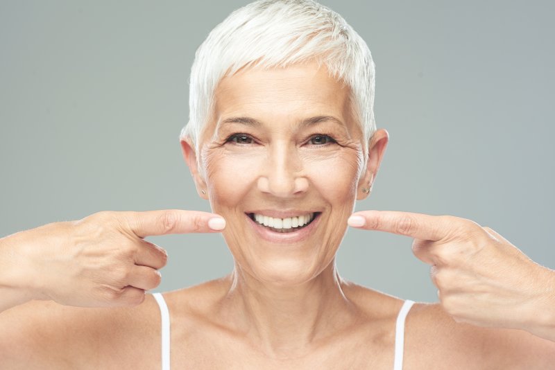 older woman pointing to fully restored smile