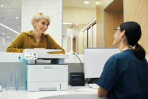 a patient speaking with a front office worker in a dental office