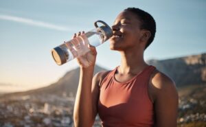 Woman drinking water from a glass bottle.