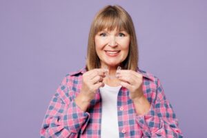 Middle-aged woman holding clear aligner.